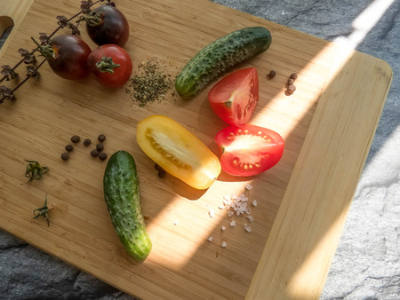 red and yellow tomatoes sliced and cucumber on a wooden board. healthy eating. eco-friendly products. Organic Food. Style Top View Group Objectsの写真素材