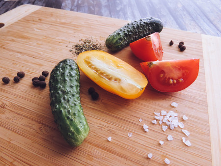 red and yellow tomatoes sliced and cucumber on a wooden board. healthy eating. eco-friendly products. Organic Food. Style Top View Group Objectsの写真素材