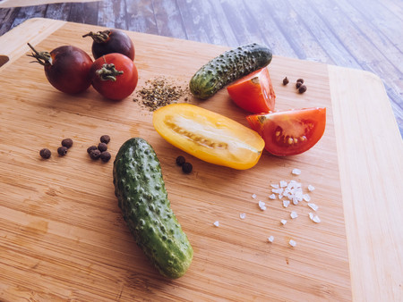 red and yellow tomatoes sliced and cucumber on a wooden board. healthy eating. eco-friendly products. Organic Food. Style Top View Group Objectsの写真素材