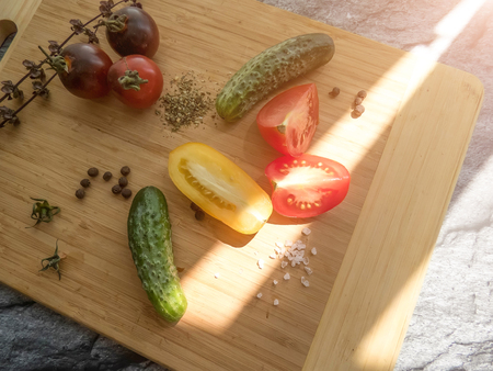 red and yellow tomatoes sliced and cucumber on a wooden board. healthy eating. eco-friendly products. Organic Food. Style Top View Group Objectsの写真素材