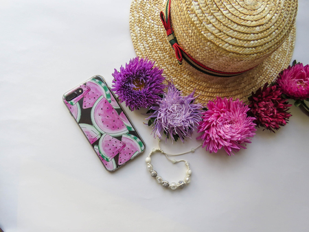 Stylized feminine flatlay with hat, bunch of aster, bracelet and smart phone mock up isolated on white top view. Woman accessories from above. Group Objects copy spaceの写真素材