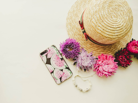Stylized feminine flatlay with hat, bunch of aster, bracelet and smart phone mock up isolated on...