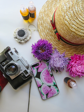 Stylized feminine flatlay with camera, hat, bunch of aster, bracelet and smart phone mock up isolated on white top view. Woman accessories from above. Group Objectsの写真素材