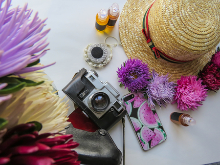 Stylized feminine flatlay with camera, hat, bunch of aster, bracelet and smart phone mock up isolated on white top view. Woman accessories from above. Group Objectsの写真素材