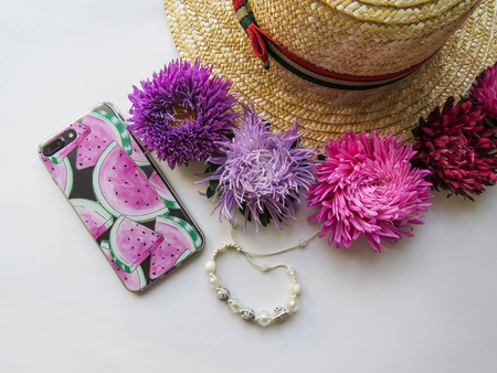 Stylized feminine flatlay with hat, bunch of aster, bracelet and smart phone mock up isolated on white top view. Woman accessories from above. Group Objects copy spaceの写真素材