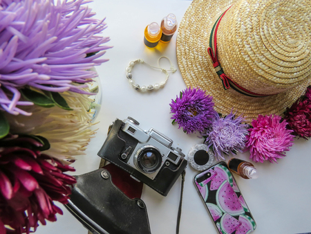 Stylized feminine flatlay with camera, hat, bunch of aster, bracelet and smart phone mock up isolated on white top view. Woman accessories from above. Group Objectsの写真素材