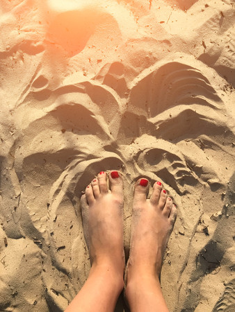 Woman tanned legs on sand beach. Travel concept. Happy feet in tropical paradise Style Top Viewの写真素材