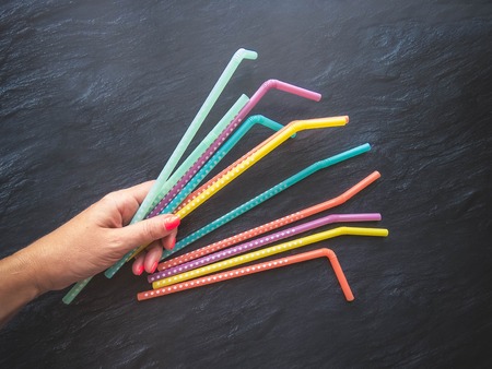 Drinking paper colorful straws in hand for summer cocktails on dark background with copy space. Top view. group of objectsの写真素材