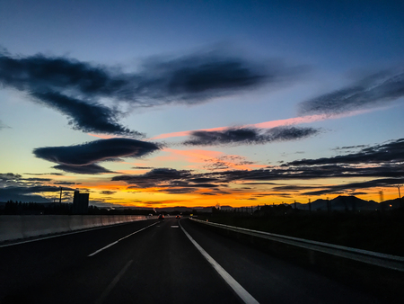 Dramatic image of Panoramic view with A long curve road in the early morning against sunrise sky,cloudy and foggy, Slovakiaの写真素材