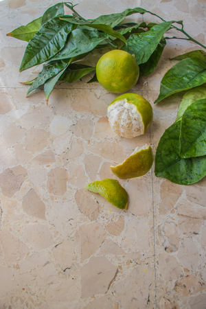 tangerigreen tangerines on a branch with green leaves on a light marble background. group of objects top viewの写真素材