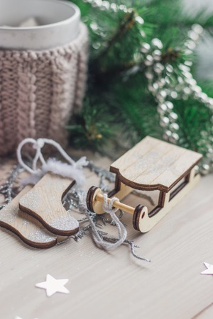 White cup for cocoa in beige knitted clothes. Santa Claus sleigh. socks on a white wooden background with christmas tree space for textの写真素材