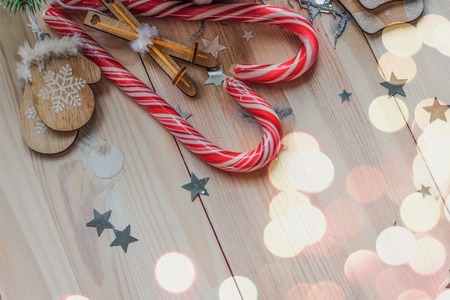 White cup for cocoa in beige knitted clothes. mittens on a white wooden background with christmas tree and red caramel candy space for textの写真素材