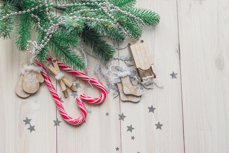 Santa Claus sleigh, mittens, hat, sweater and socks on a white wooden background with christmas tree and red caramel candy space for textの写真素材