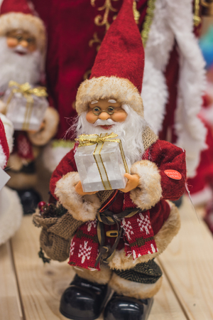 Santa Claus as Toy in red suit costume in a cap and gold-rimmed glasses with a blush on the cheeks carry gifts sale, market, realization in the shop, supermarketの写真素材