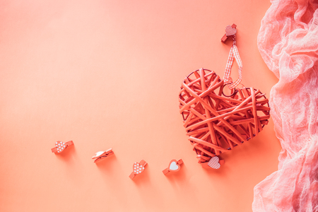 Valentines Day concept. Wicker heart and small clothespins with hearts on a coral background. field for text.の写真素材