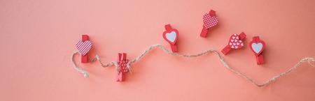Valentine's Day concept. Small clothespins with hearts on a coral background. field for text. top viewの写真素材