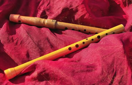 Two wooden old flutes on a rough red fabricの写真素材