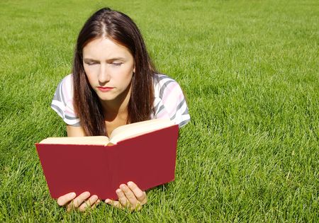 Young women with red book on the green grassの写真素材