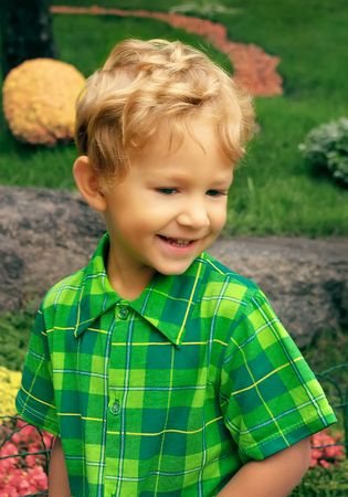 Portrait of a little smiling blond boy in the gardenの写真素材