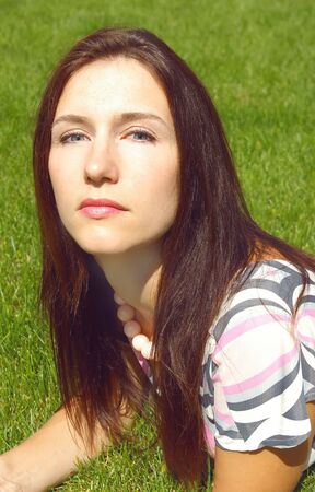 Portrait of a young beautiful women on the green grass backgroundの写真素材