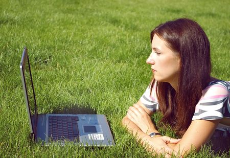Young beautiful woman, lying on the grass with the laptopの写真素材