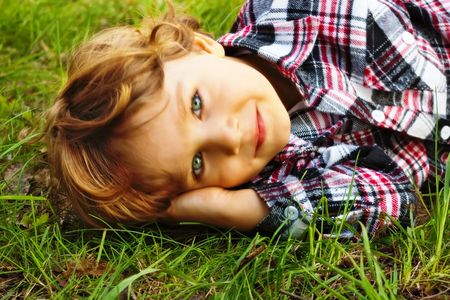 Portrait of a little smiling  boy lying in the grassの写真素材