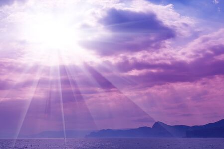 Dramatic   sea with sun rays and clouds in pink colors
