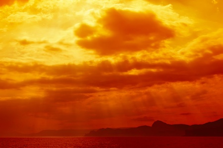 Dramatic   sea with sun rays and clouds in golden orange  colorsの写真素材