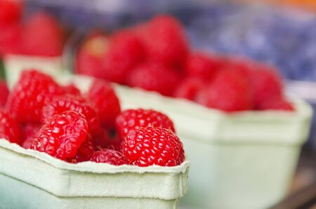 Fresh raspberry in paper box at market, local food organic healthy background