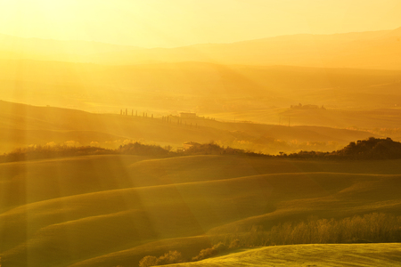 Wavy fields in Tuscany at sunrise, Italy. Natural outdoor seasonal autumn background with sun shiningの写真素材