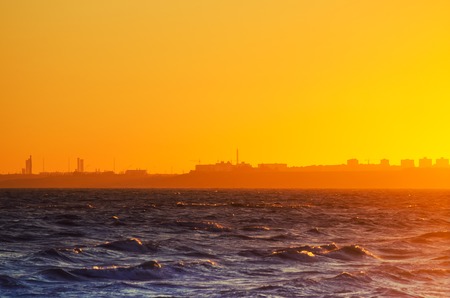 Beautiful red sunset over the sea with urbun city buildings at the horizonの写真素材