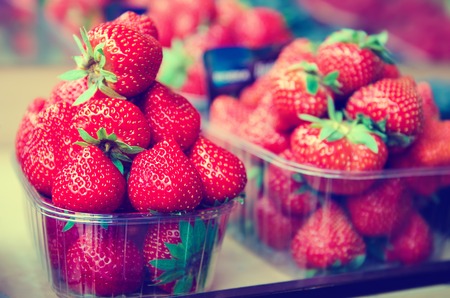 Fresh strawberry at market in plastic boxes, local food healthy background in vintage hipster styleの写真素材