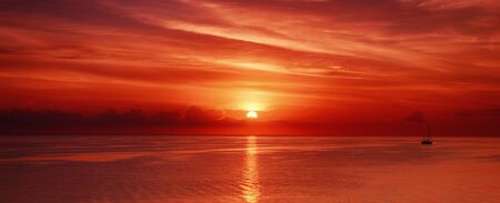 Beautiful colorful sunrise at the sea with dramatic clouds and sun shiningの写真素材