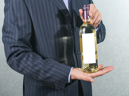 elegant man holding a bottle with a white wineの写真素材