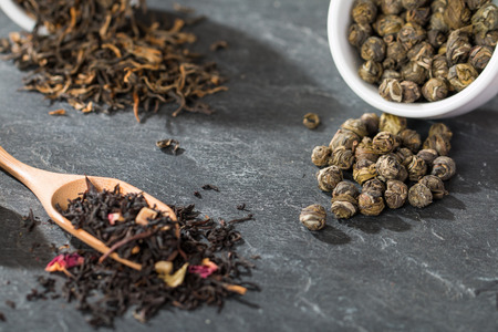 Dry tea leaves in wooden spoons, on stone backgroundの写真素材