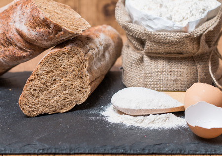 bread roll or french baguette and flour on black chalkboard.