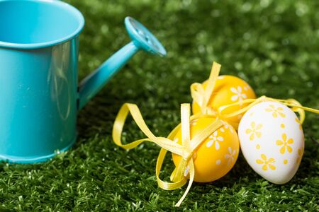 Three colorful Easter eggs with ribbons in a green grassの写真素材