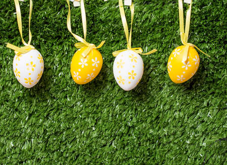 Colorful Easter eggs hanging on ribbons on grass backgroundの写真素材