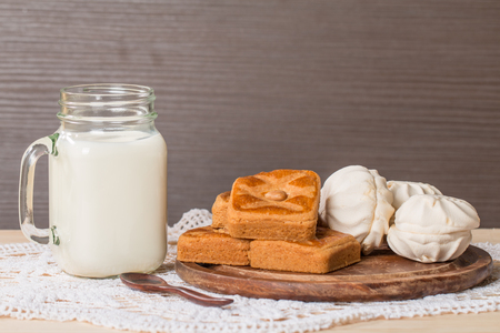 Fresh milk in glass and sweet cookies with zephyr on wooden backgroundの写真素材