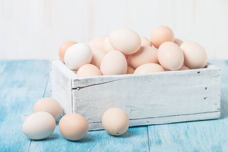 Farm fresh chicken eggs in box on blue wooden background