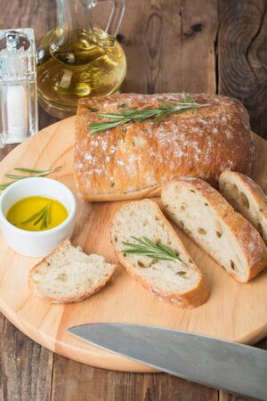 Sliced bread Ciabatta and rosemary on wooden backgroundの写真素材