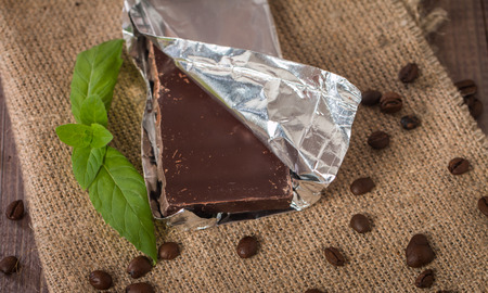 Dark chocolate with mint leaf on wooden background