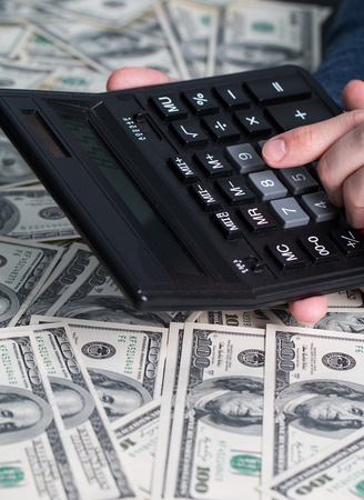 Man's hands with money and calculator. Money saving concept.の写真素材