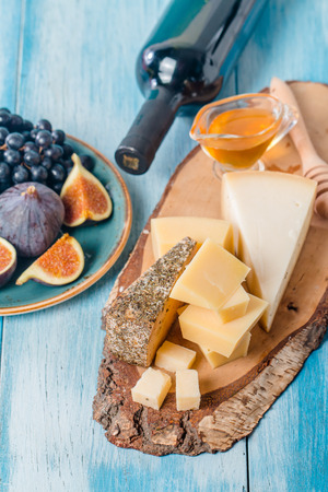 Grape, assorted cheese, figs and honey with red wine on blue wooden background.の写真素材