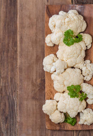 Fresh organic cauliflower in a bowl on wooden background, top viewの写真素材