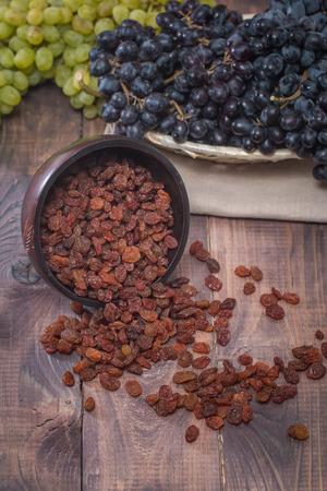 Natural organic raisins in bowl and grapes on old rustic tableの写真素材