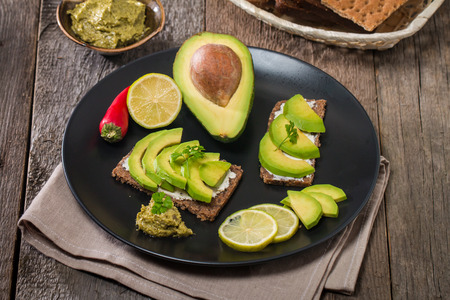 Avocado sandwich with ingredients in plate on wooden backgroundの写真素材