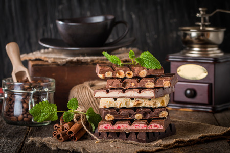An assortment of white, dark, and milk chocolate with nuts and with various fillings on wooden backgroundの写真素材