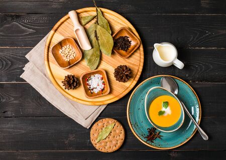 Pumpkin and carrot soup with cream and seasoning in blue bowl  on black wooden background, top viewの写真素材
