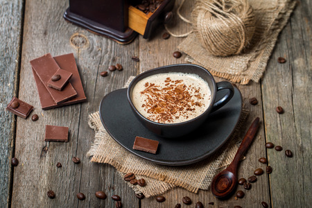 Cup of coffee with coffee beans and chocolate on wooden tableの写真素材